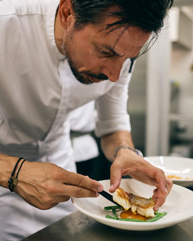 Charalabopoulos bent over the pass in Amoni's kitchen, finishing a plate