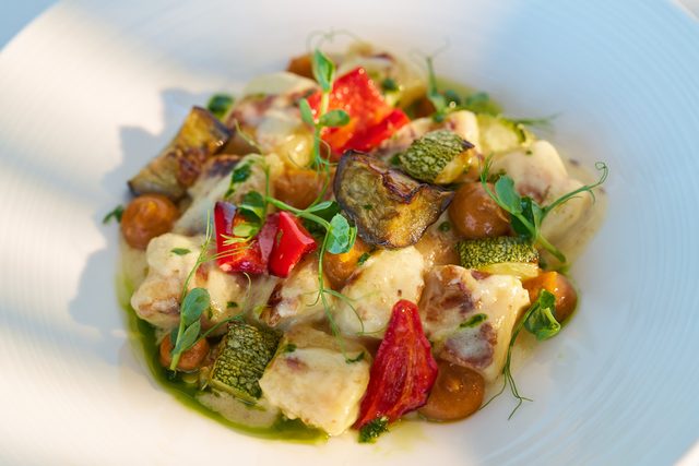 Soft gnocchi with roast aubergine, courgette, red pepper and confit cherry tomatoes, finished with green oil and pea shoots